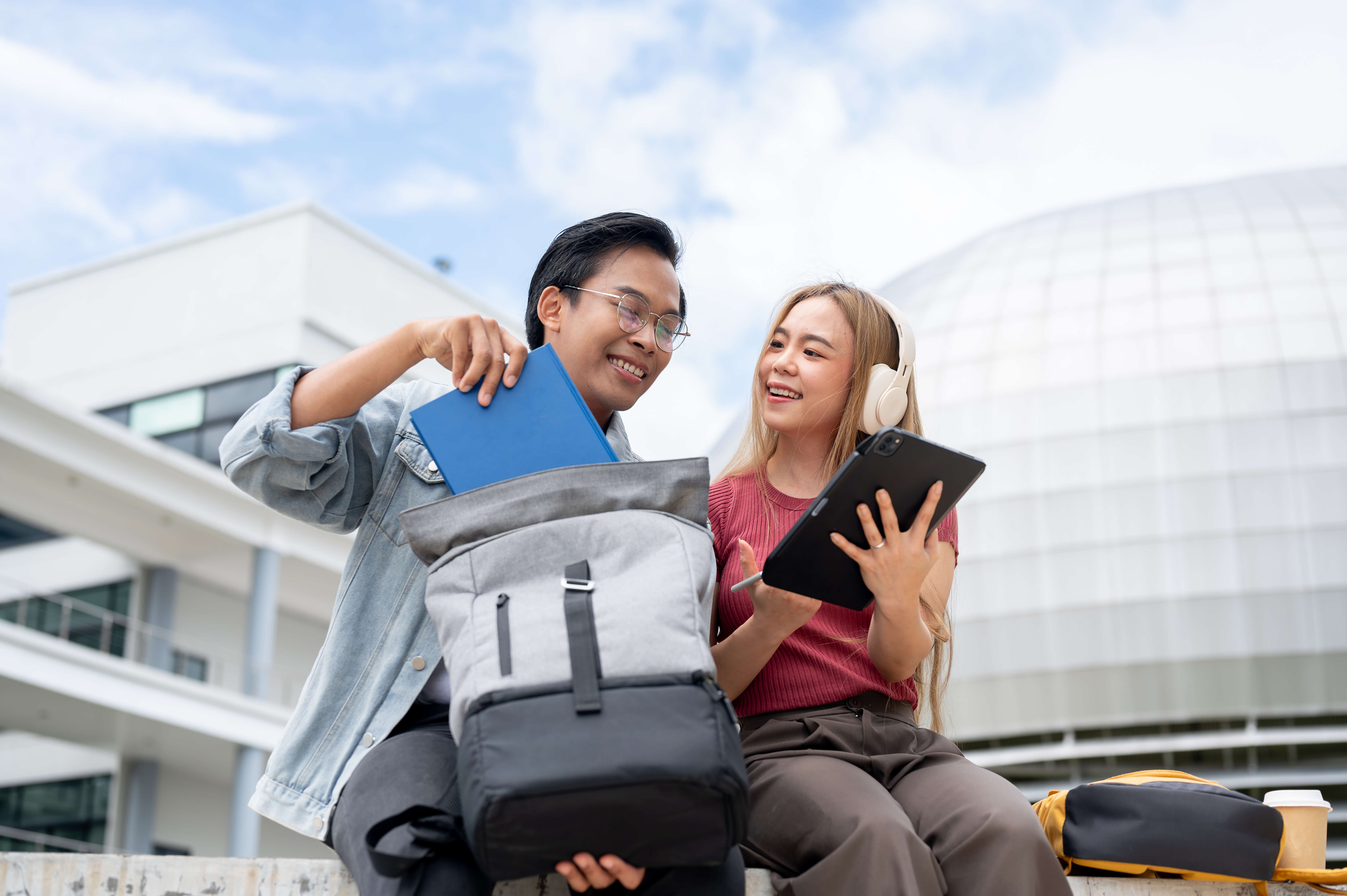 two-cheerful-asian-college-students-are-having-good-conversation-while-relaxing-outdoors-campus two-cheerful-asian-college-students-are-having-good-conversation-while-relaxing-outdoors-campus